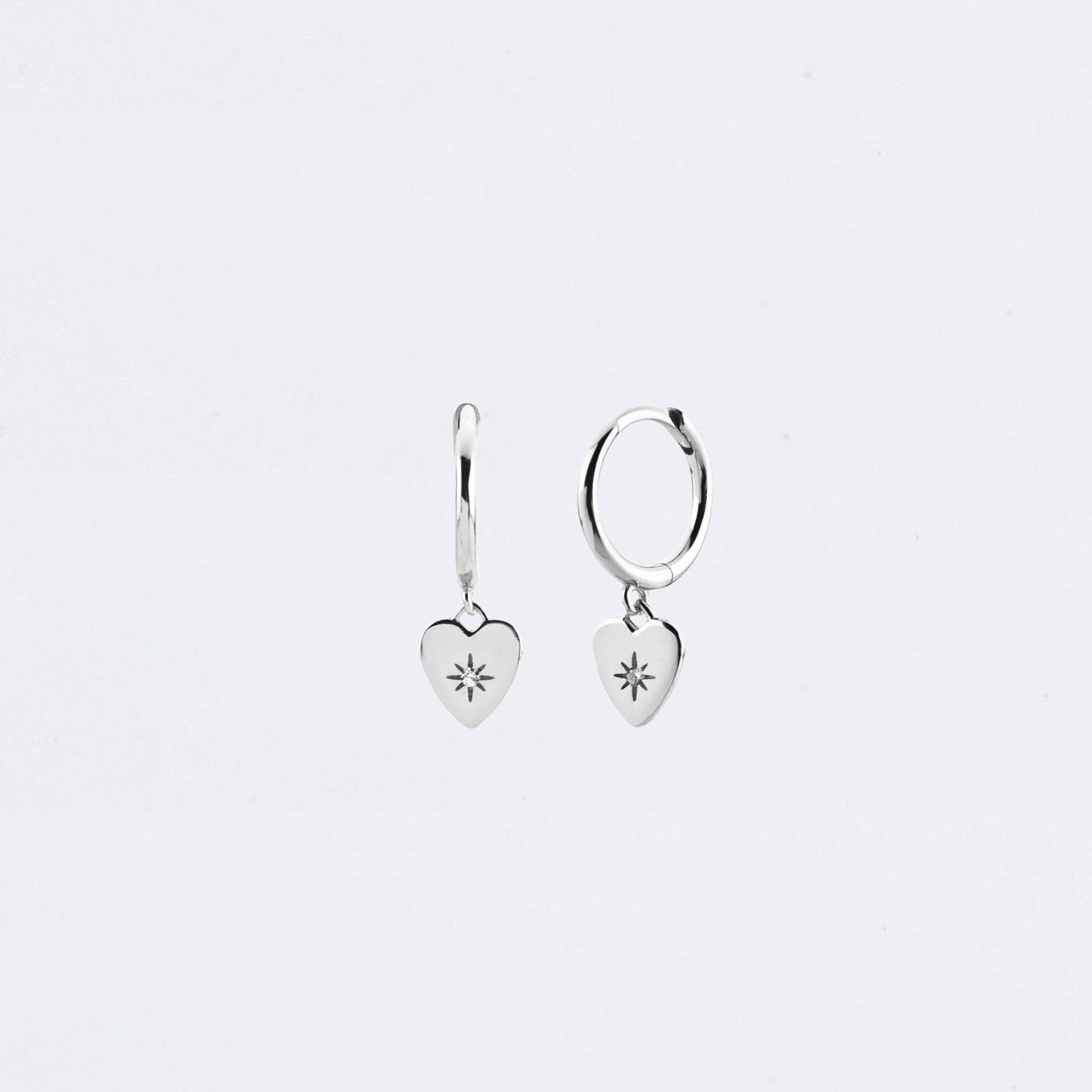 Gold heart-shaped earrings on a light gray background Maraux Love Heart Huggies Maraux Jewellery