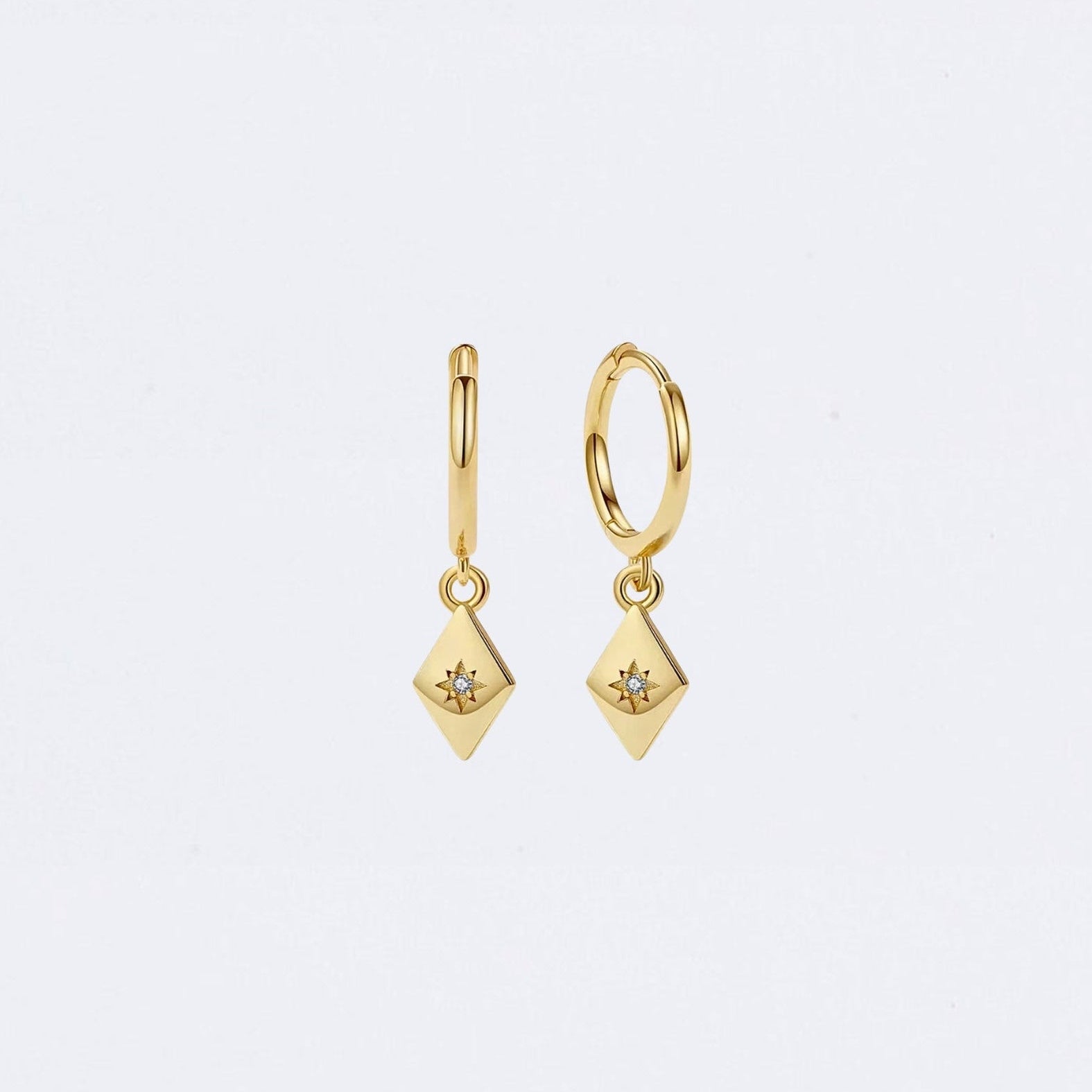 Gold earrings with diamond-like stones on a light gray background Maraux Petite Diamond-Shaped Huggie Earrings MarauxJewellery
