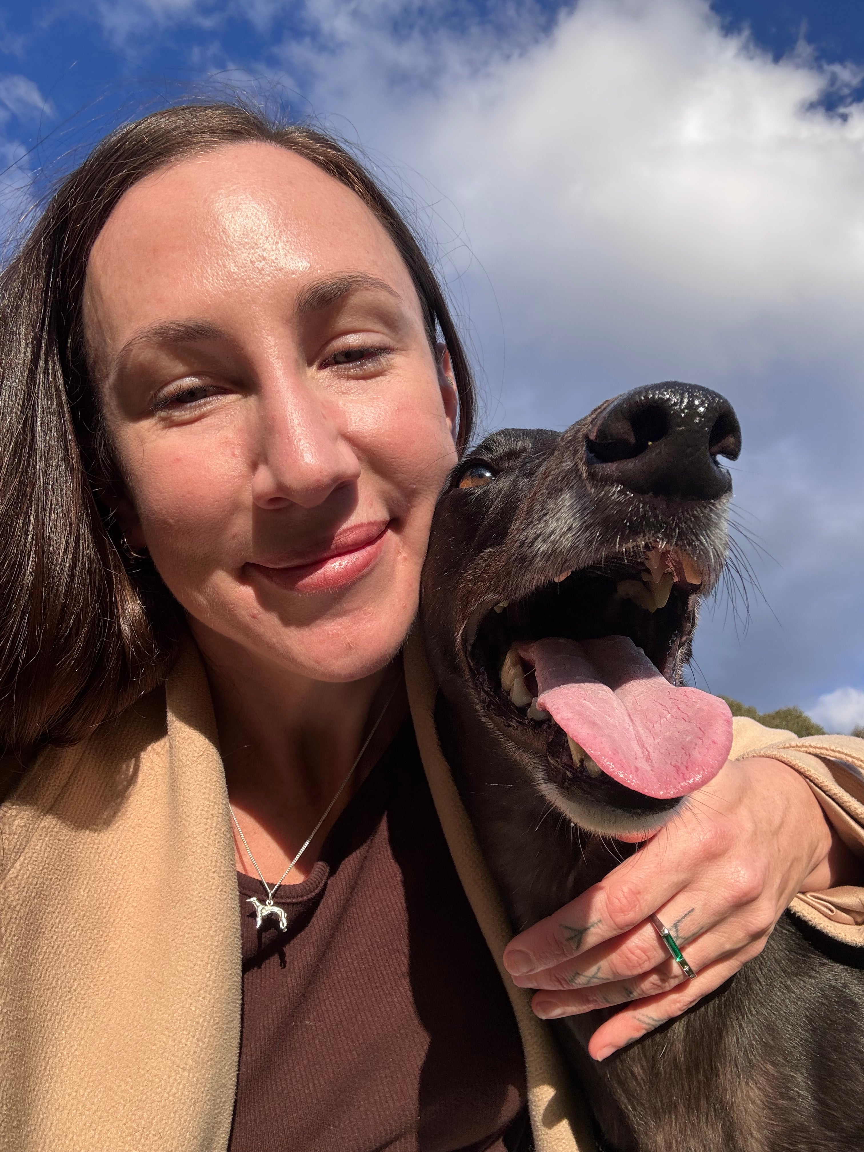 Customer wearing the Greyhound Rescue Necklace with her rescued greyhound