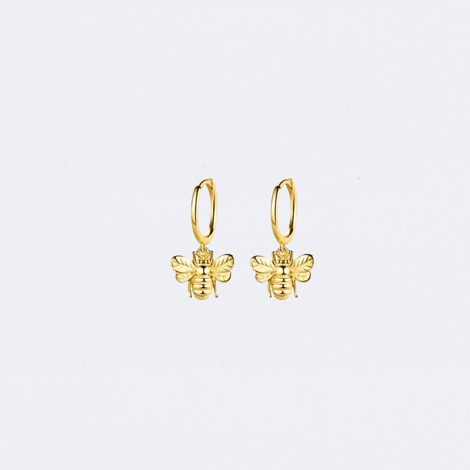 Gold bee-shaped earrings on a light gray background