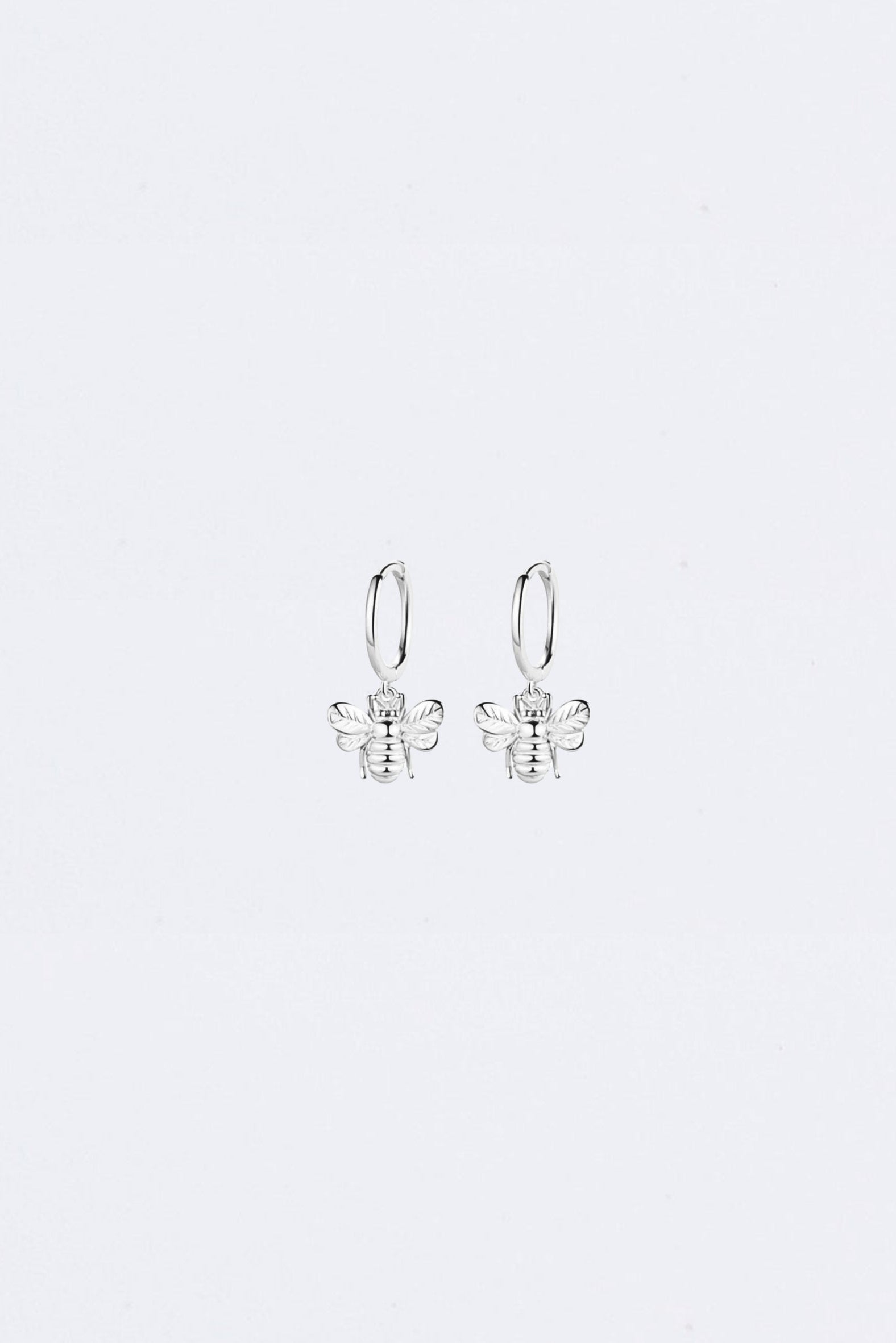 Silver bee-shaped earrings on a light gray background
