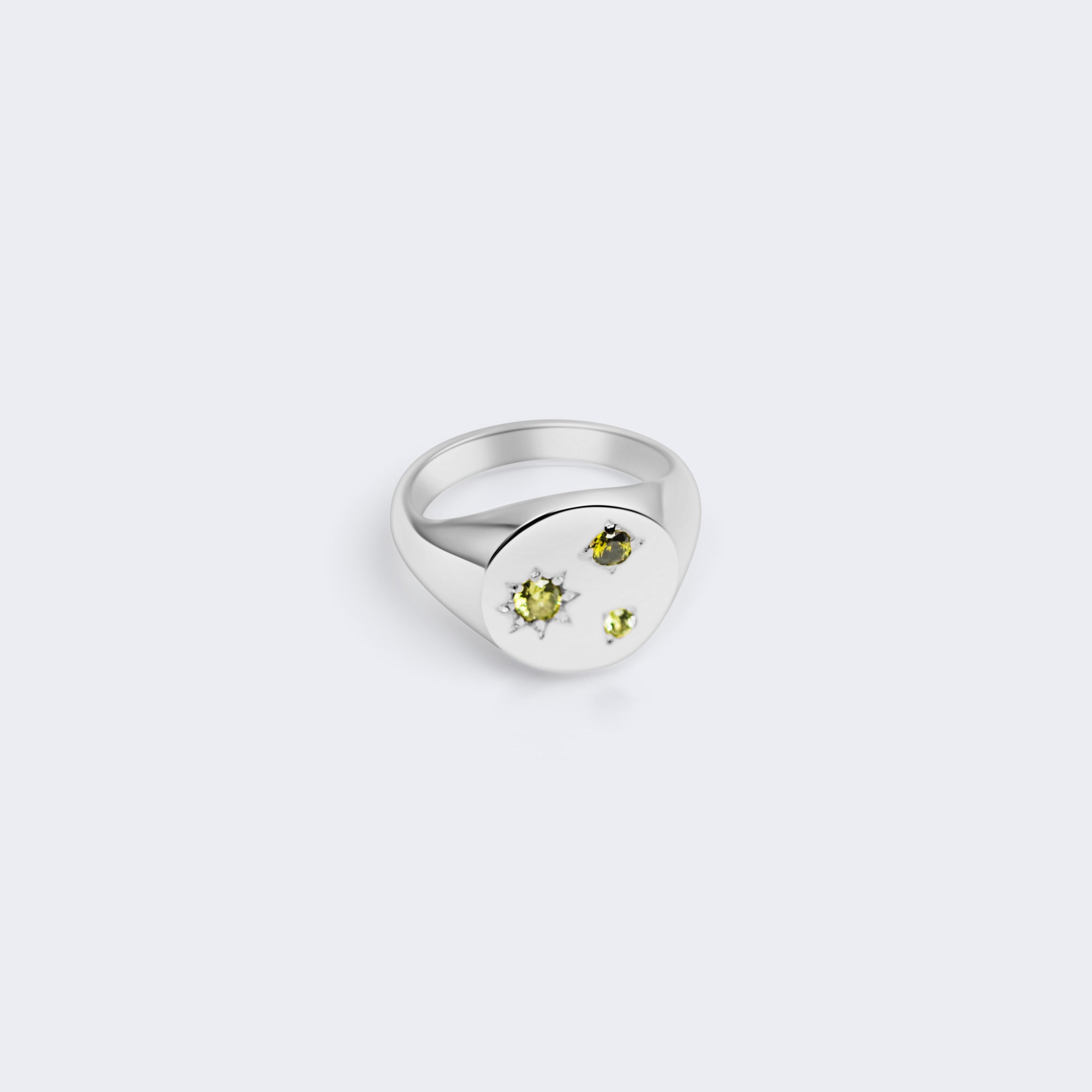 A silver signet ring featuring a heart-shaped face with three small yellow gemstones