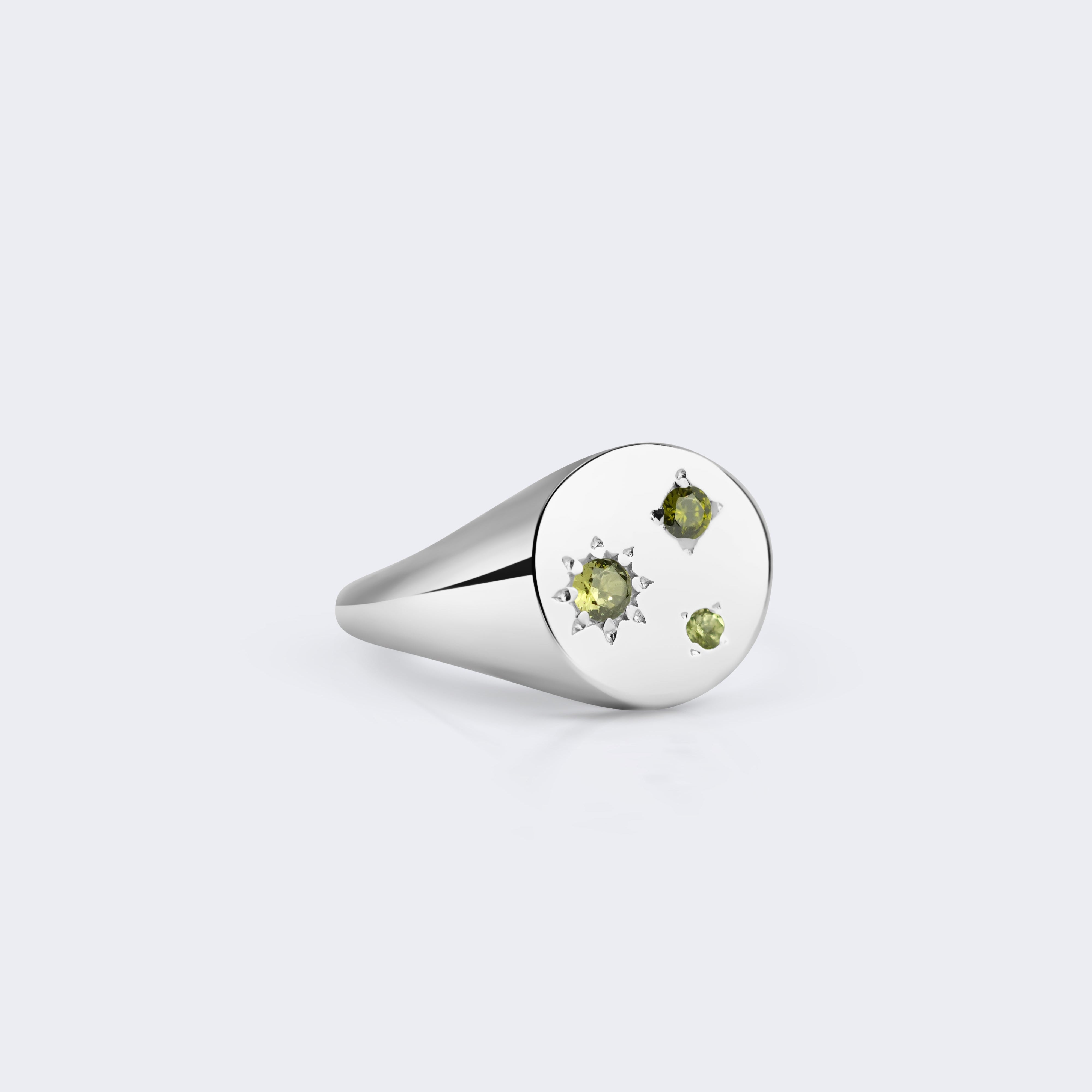 A silver signet ring with three small green gemstones set on a flat oval face