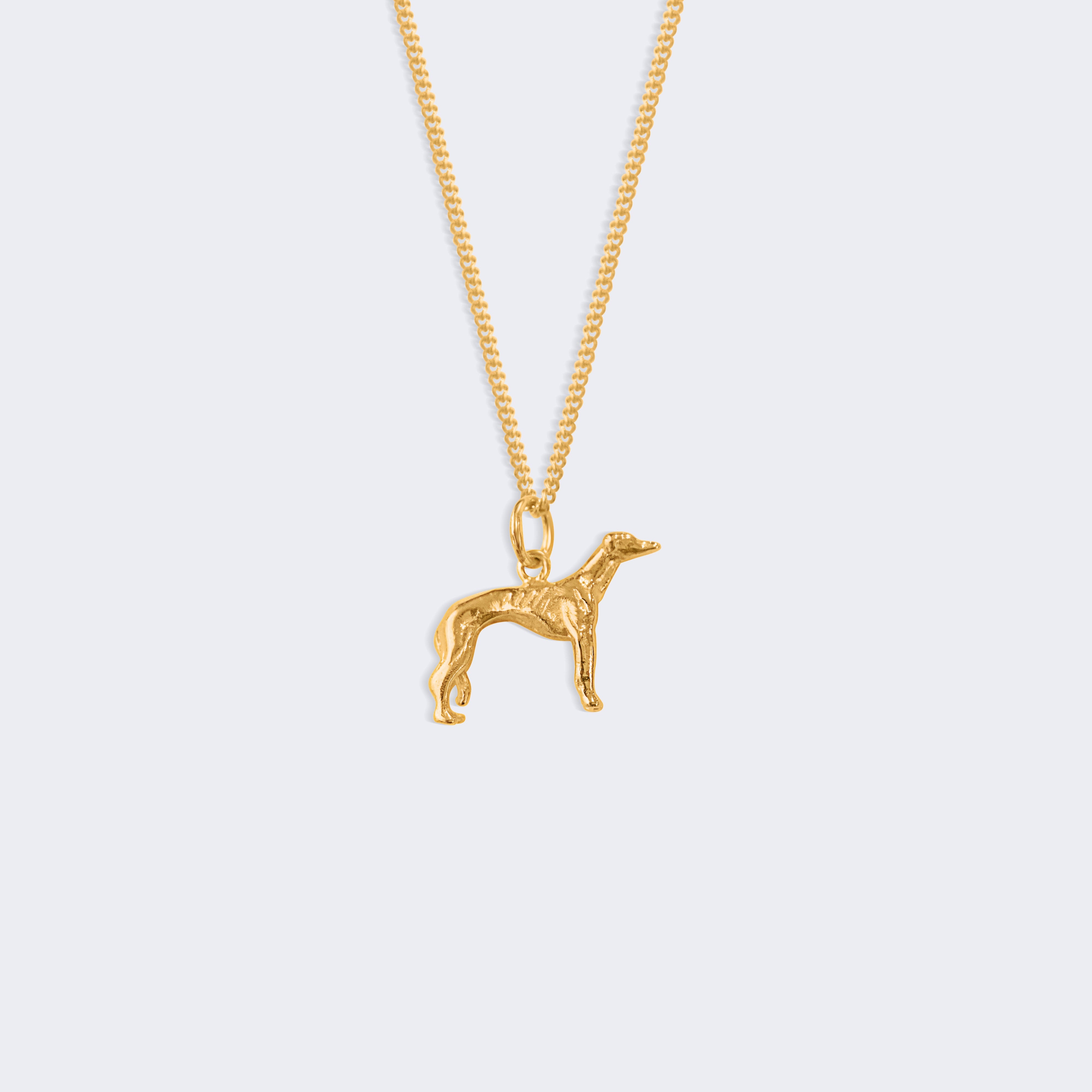 A gold chain necklace featuring a small greyhound pendant, displayed against a solid light gray background.