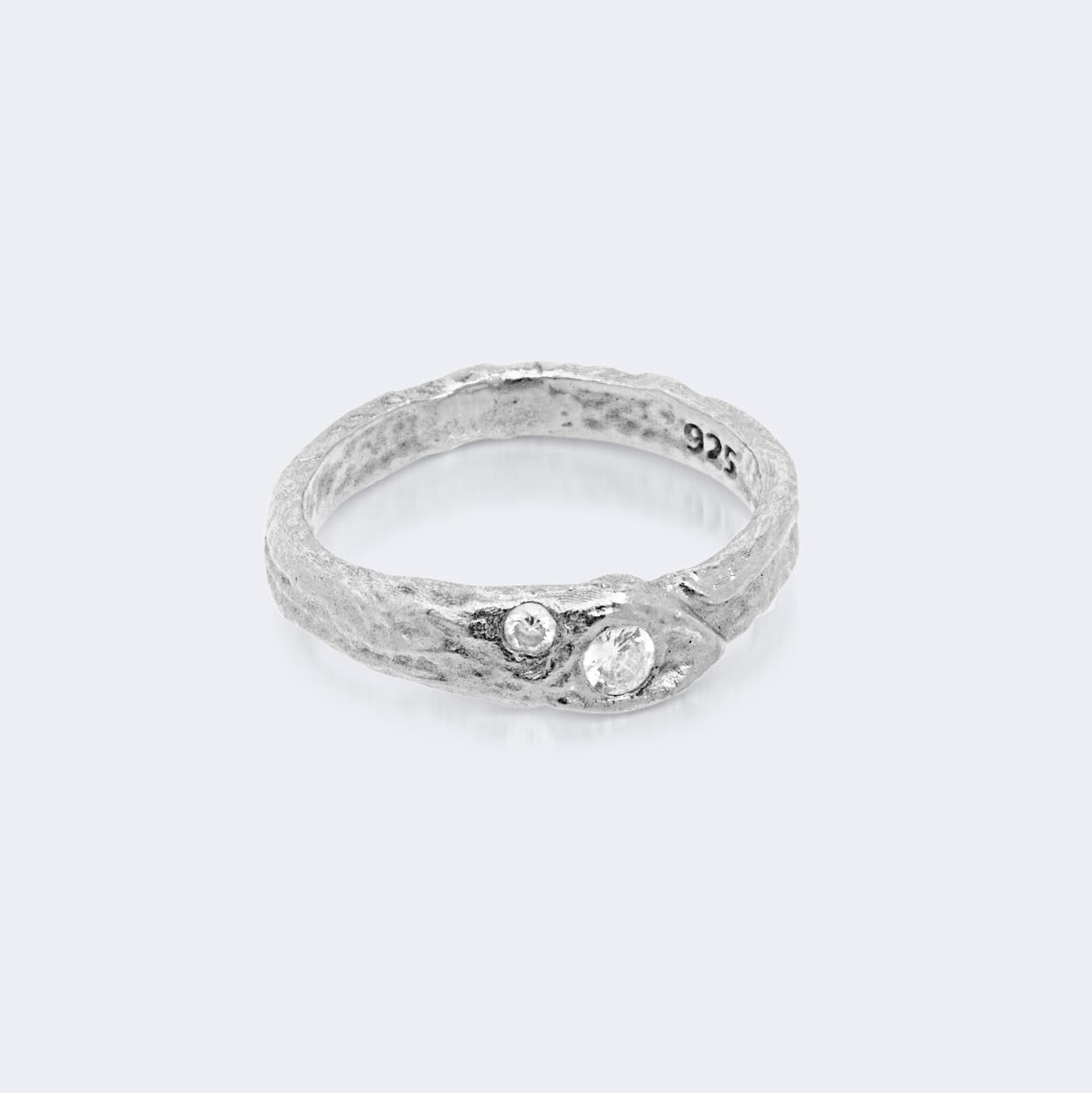 Silver ring with embedded stones on a light gray background