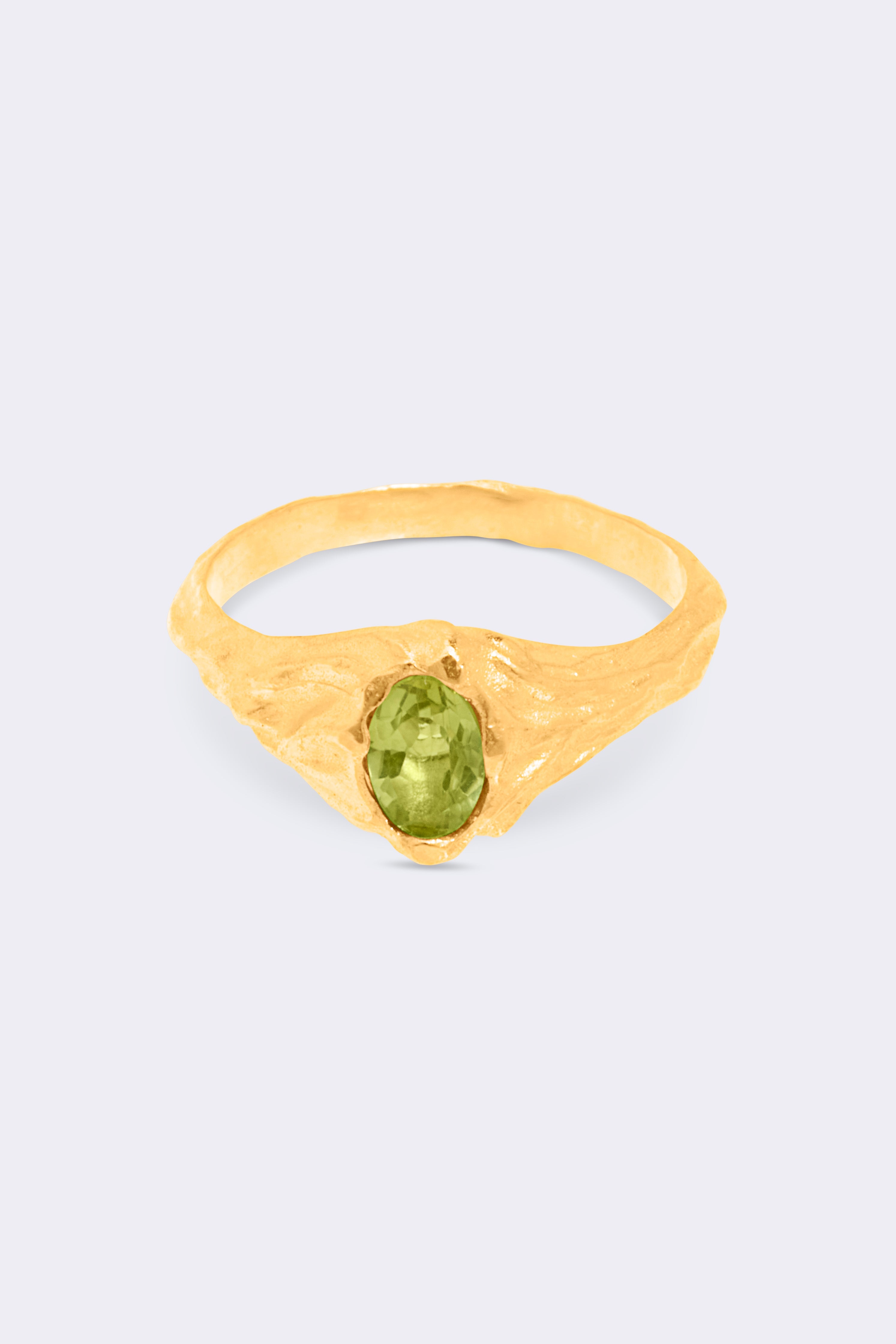 Gold ring with a green gemstone on a light gray background