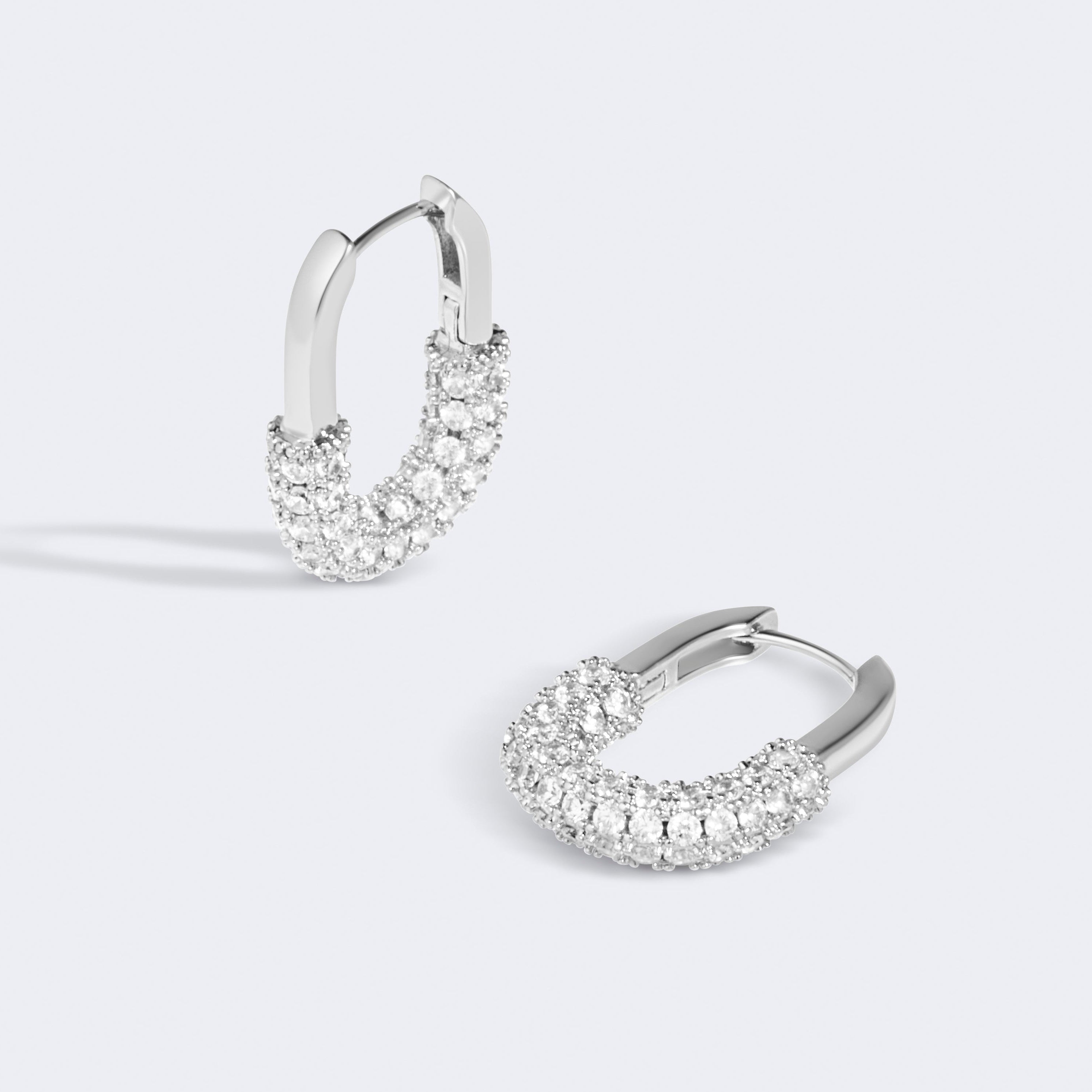 Pair of silver hoop earrings with clear gemstones on a light gray background