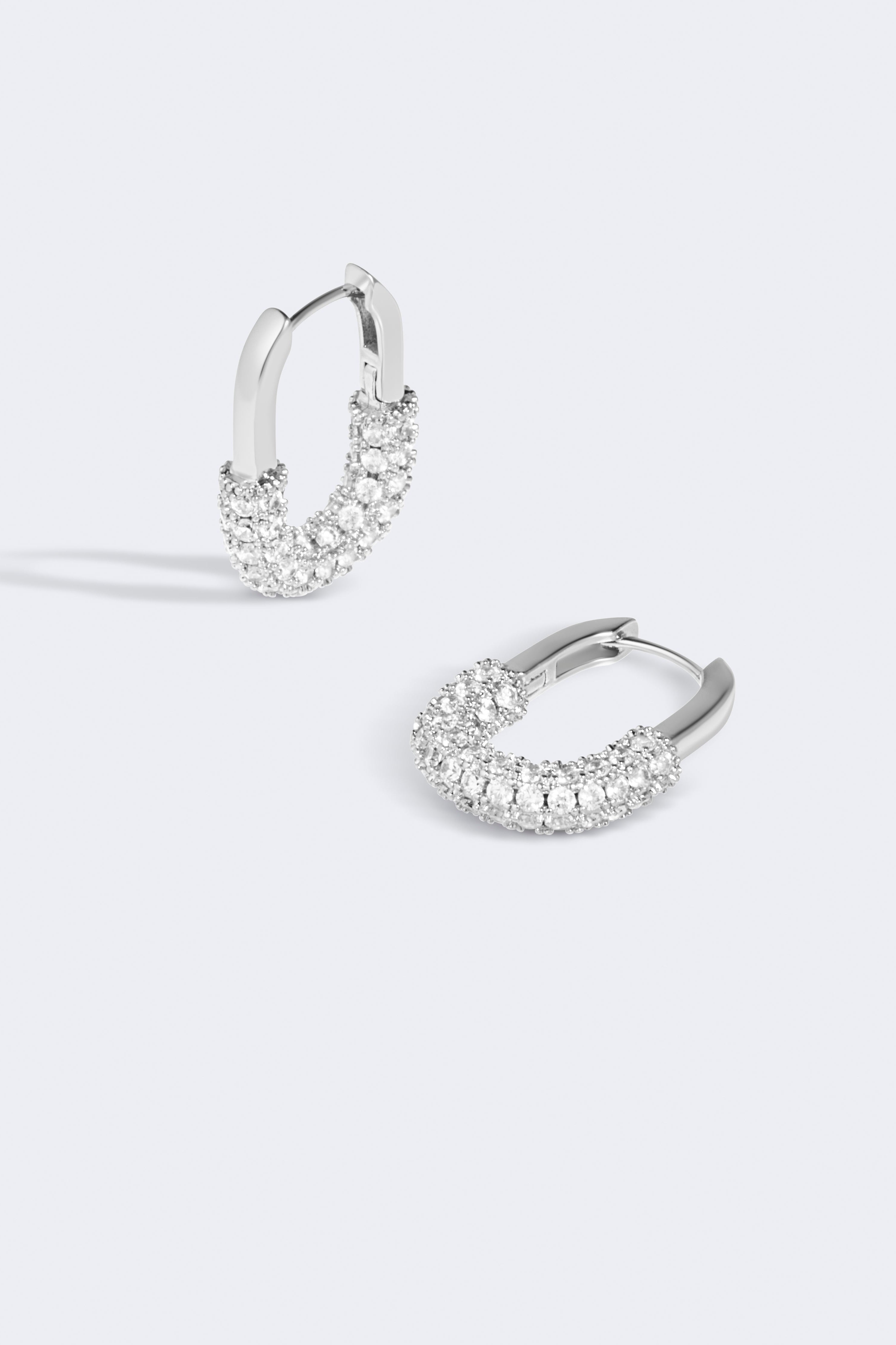 Pair of silver hoop earrings with clear gemstones on a light gray background