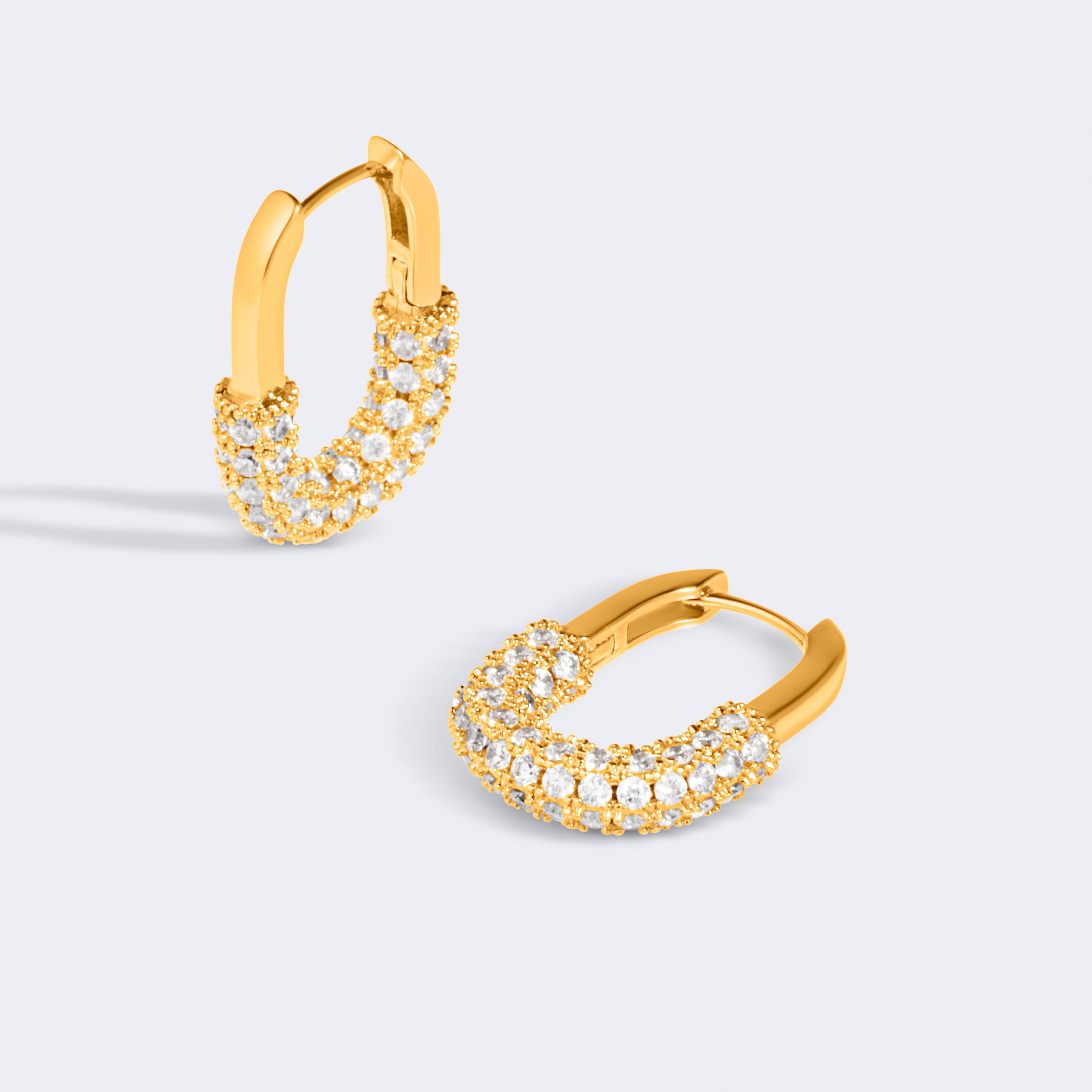 Gold hoop earrings with embedded stones on a light gray background