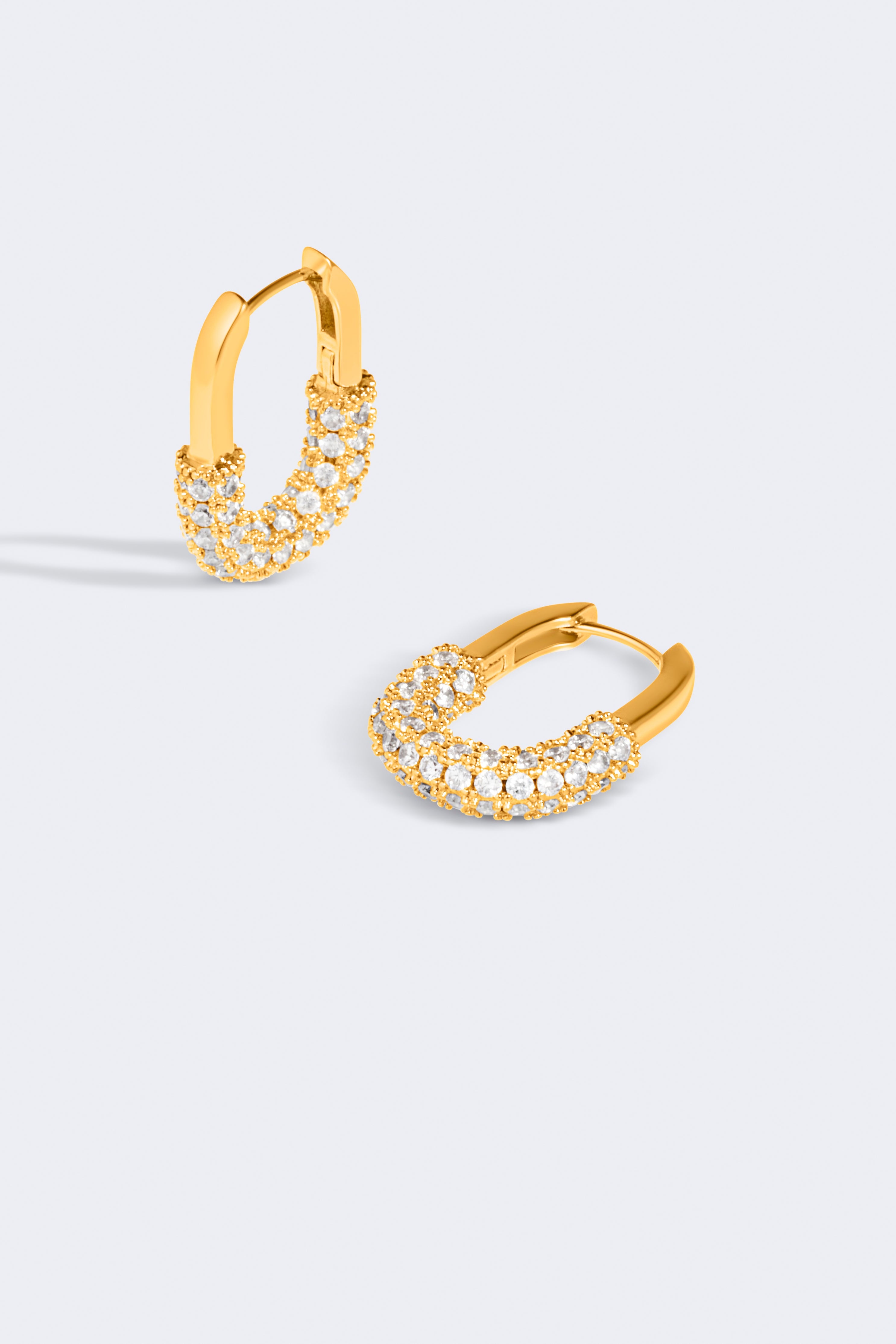 Gold hoop earrings with embedded stones on a light gray background