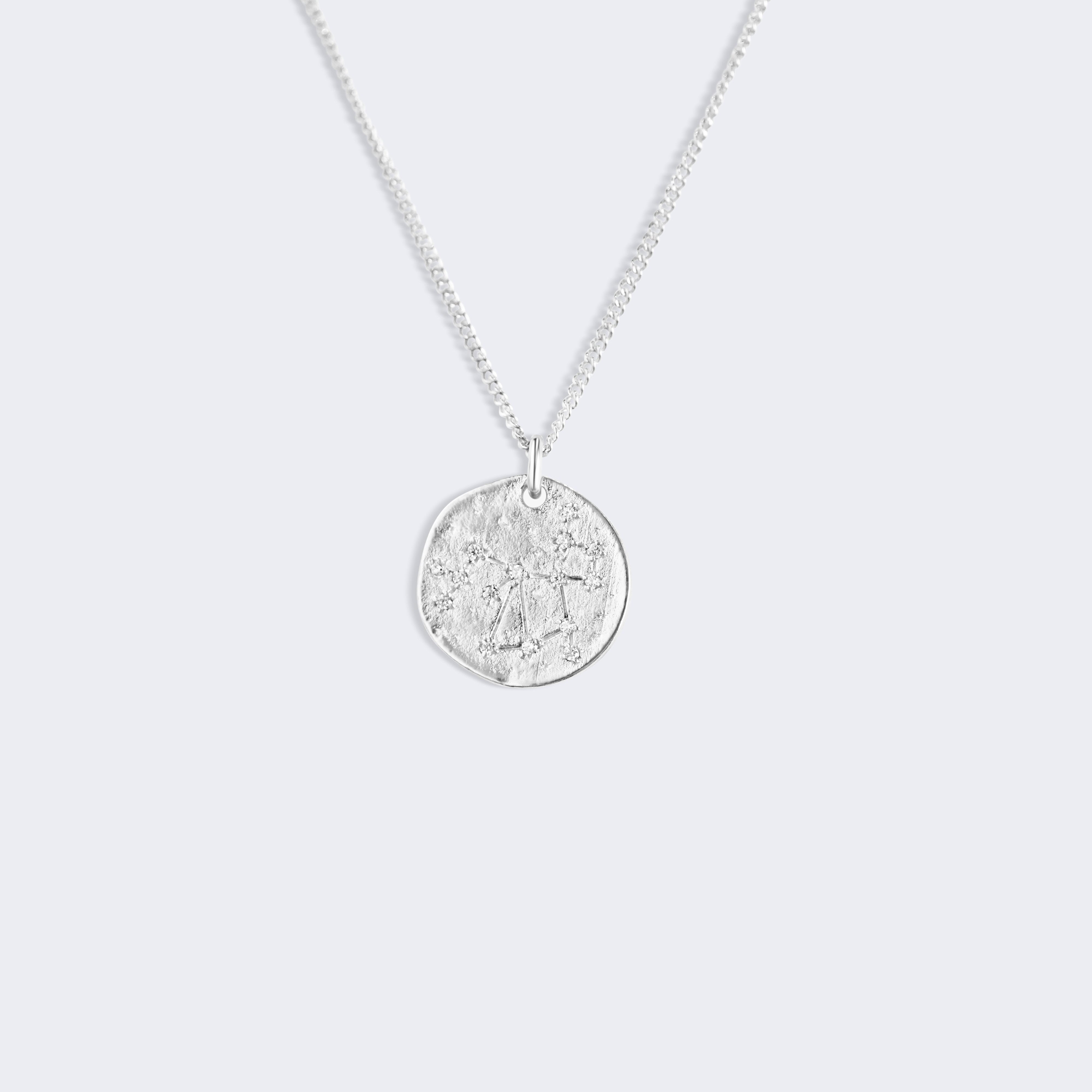 A silver chain necklace with a round, textured coin-style pendant, Sagittarius star constellation zodiac silver