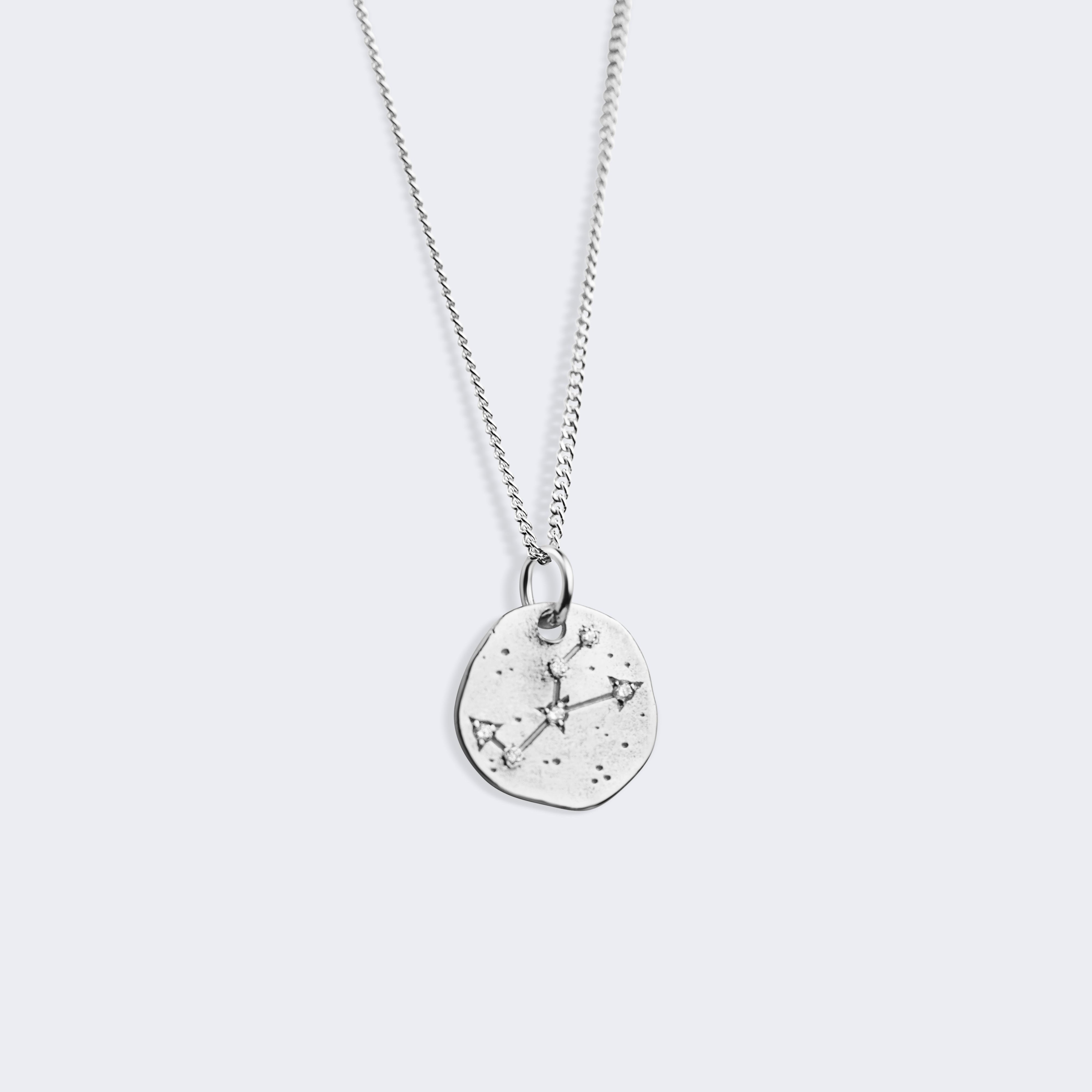 A silver chain necklace with a small, irregularly shaped silver pendant featuring a starry Taurus constellation pattern, shown against a light gray background.
