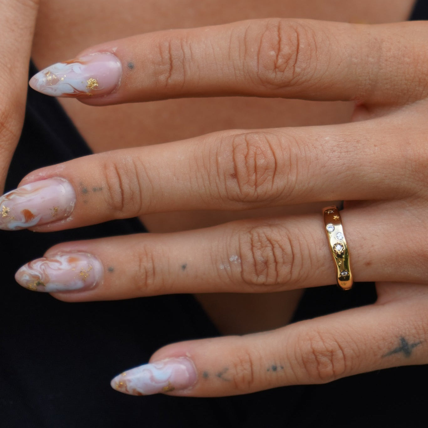 Close-up of a hand with a gold ring on a black background