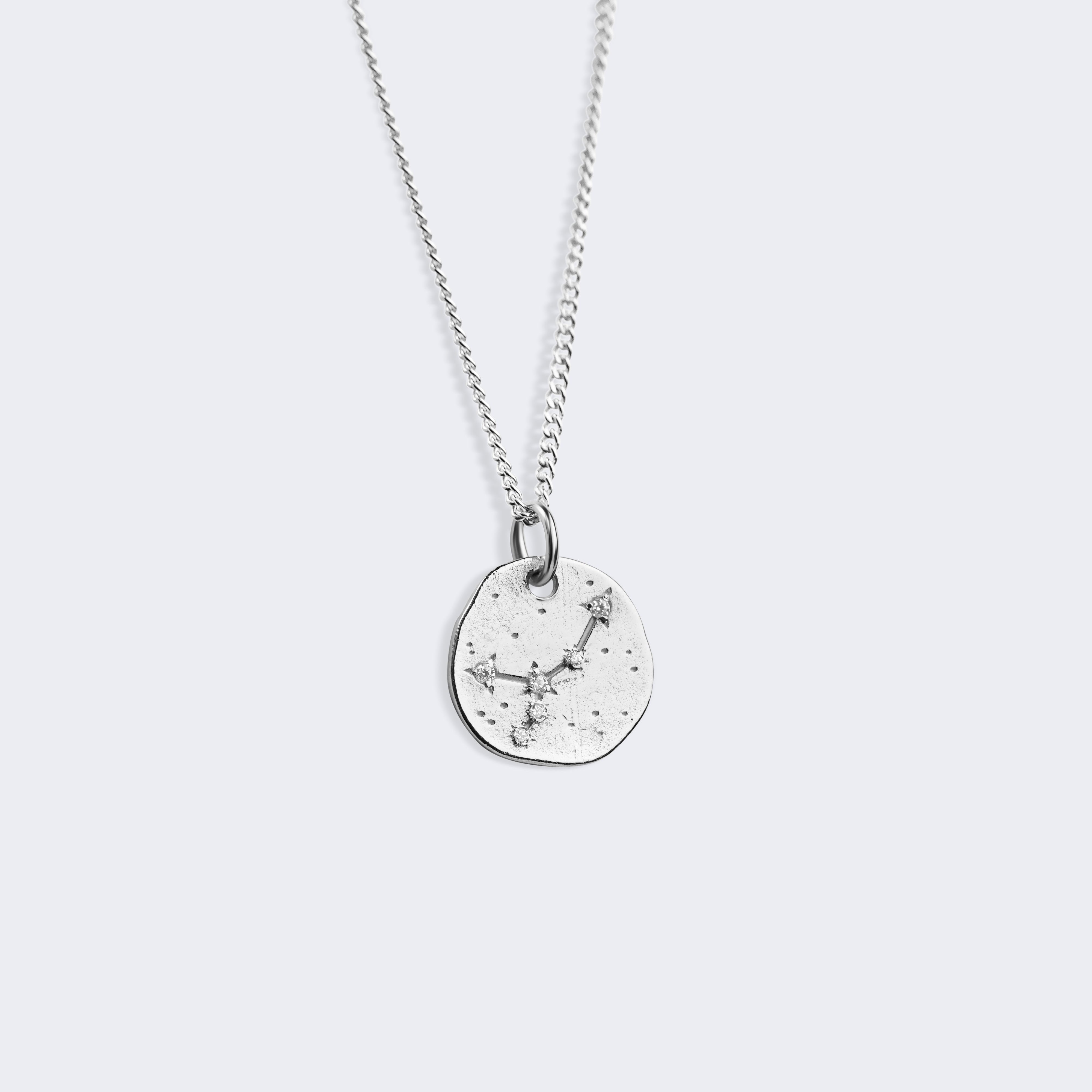 A silver chain necklace with a small, irregularly shaped silver pendant featuring a starry cancer constellation pattern