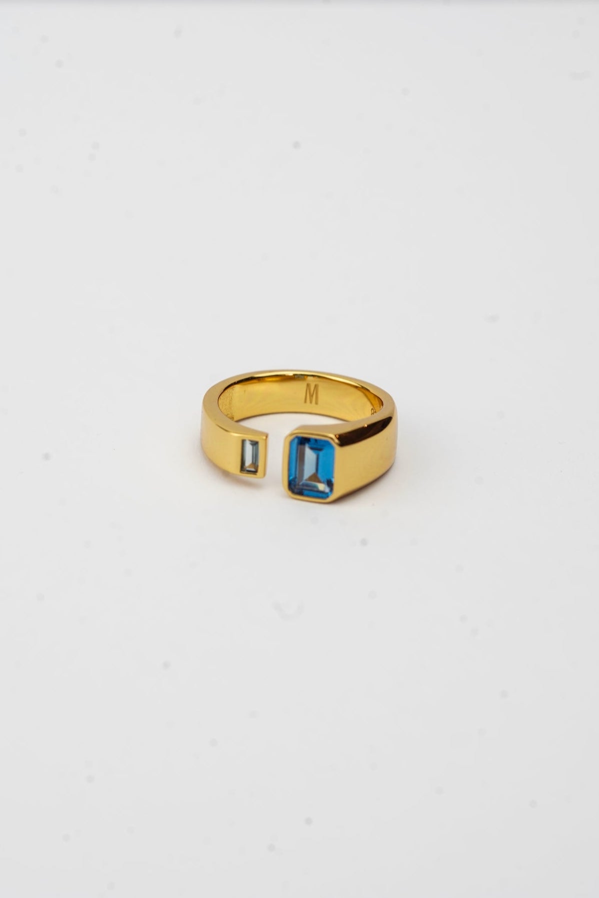 Gold ring with a blue gemstone on a white background