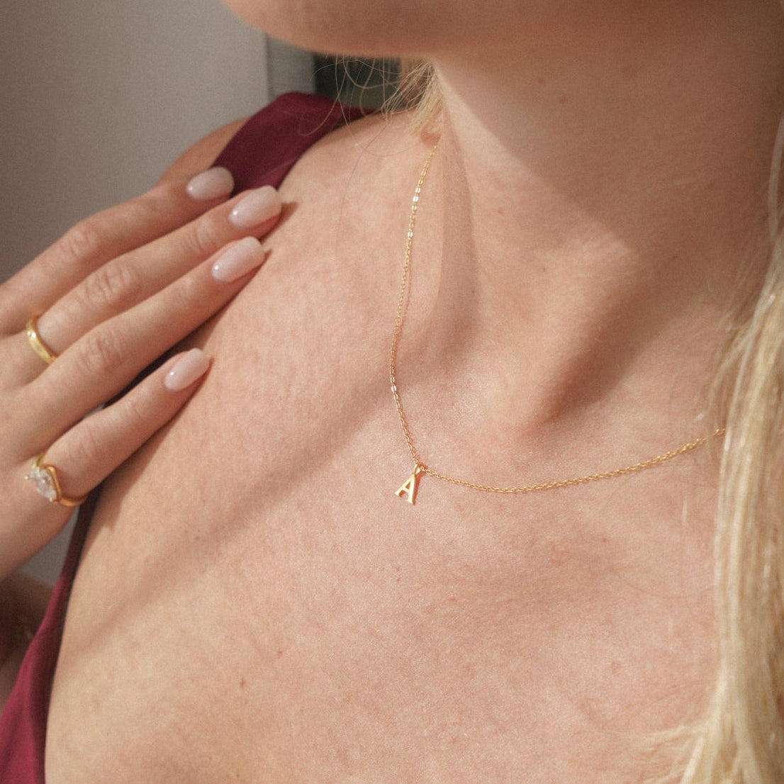Close-up of a woman wearing a gold necklace with a letter pendant.