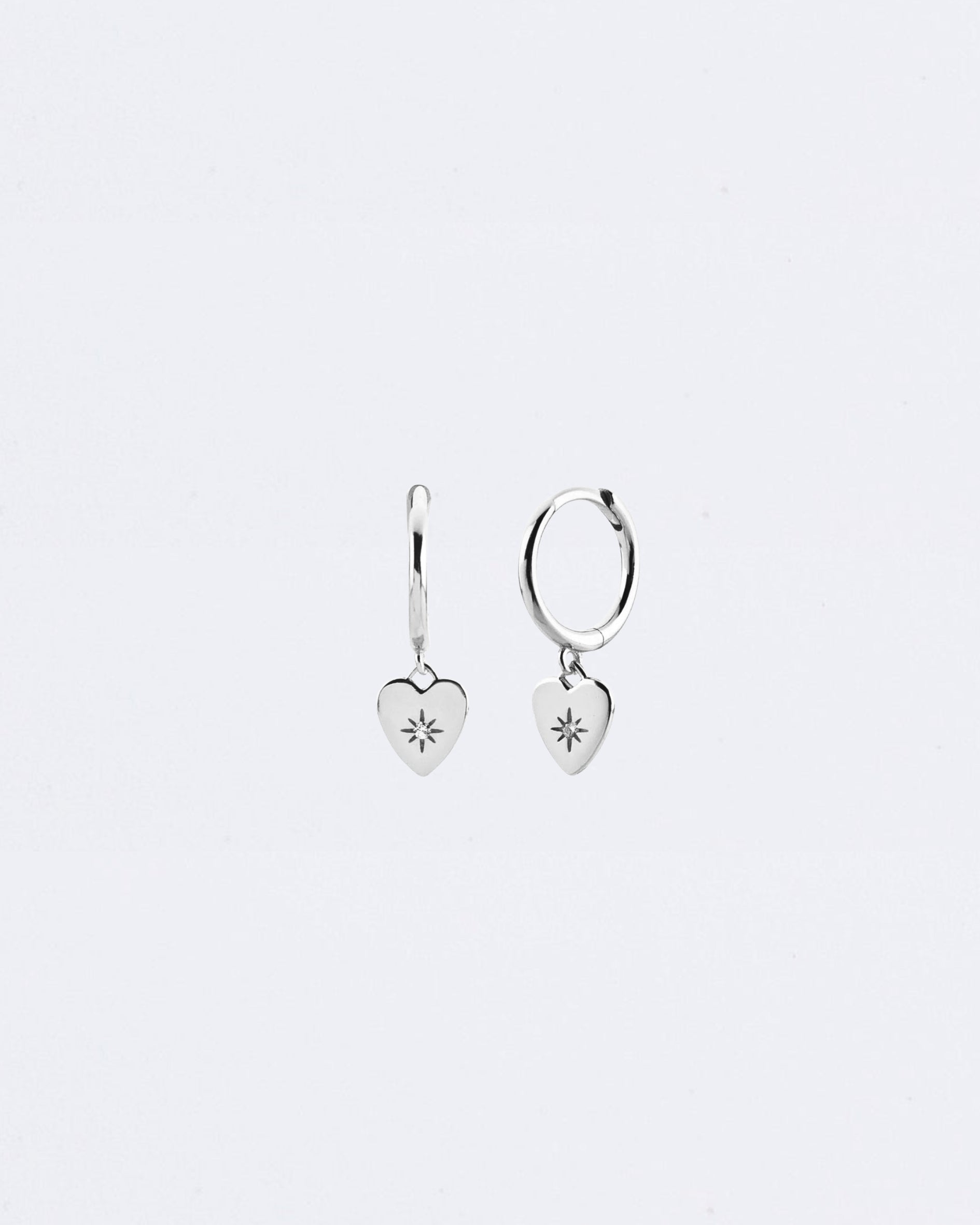 Gold heart-shaped earrings on a light gray background Maraux Love Heart Huggies Maraux Jewellery
