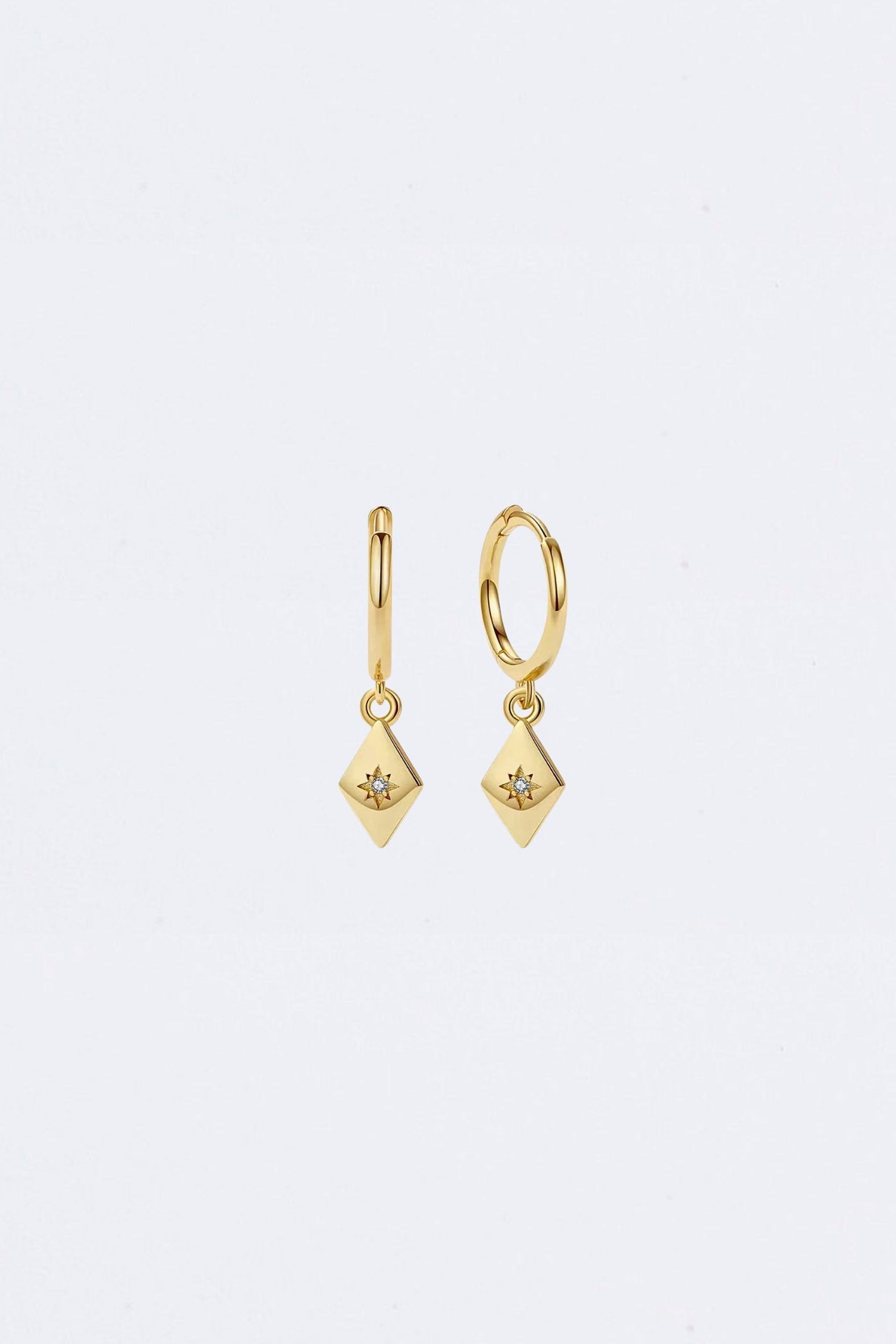 Gold earrings with diamond-like stones on a light gray background Maraux Petite Diamond-Shaped Huggie Earrings MarauxJewellery