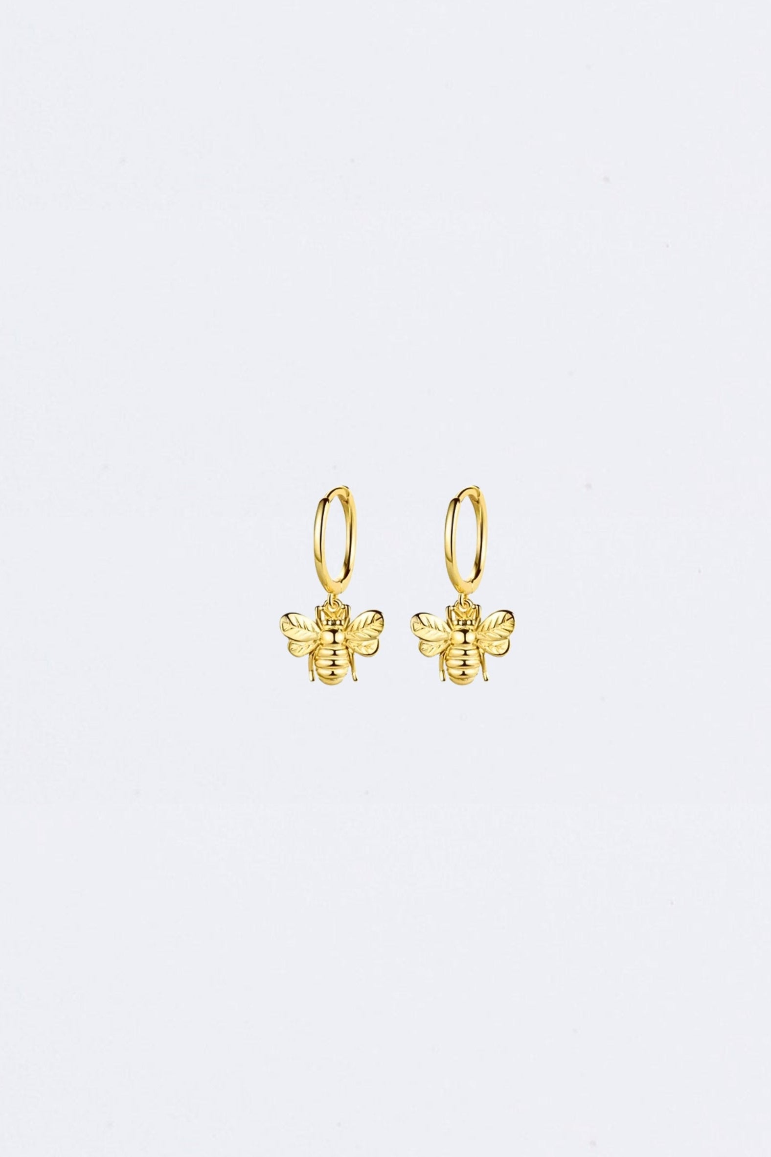 Gold bee-shaped earrings on a light gray background