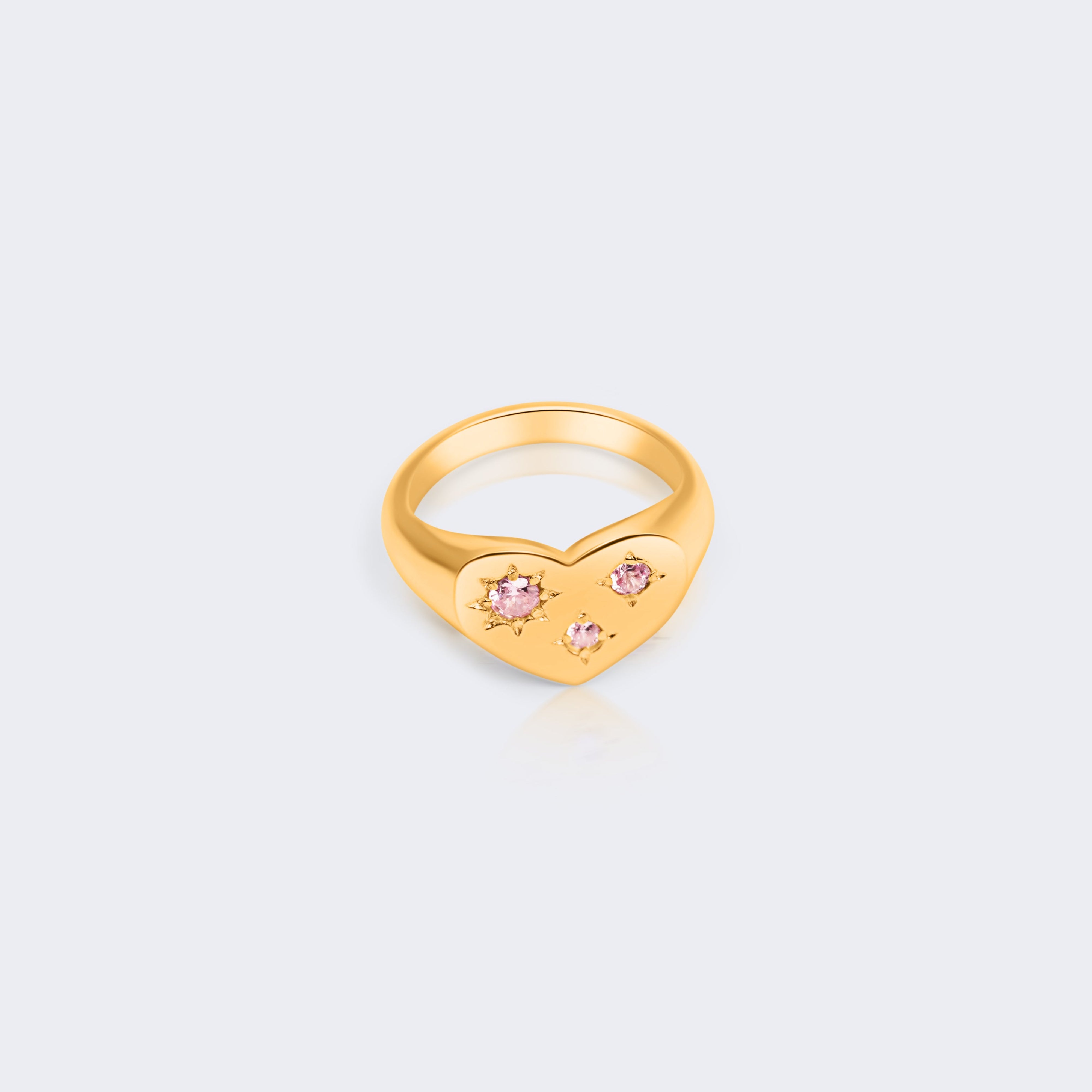 A gold ring featuring a small heart-shaped setting adorned with three tiny pink gemstones
