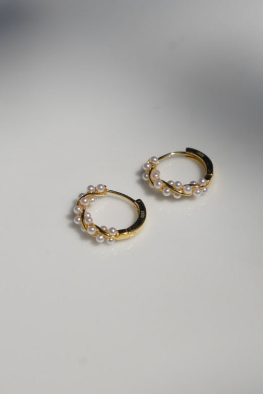 Gold hoop earrings on a white surface with a blurred background