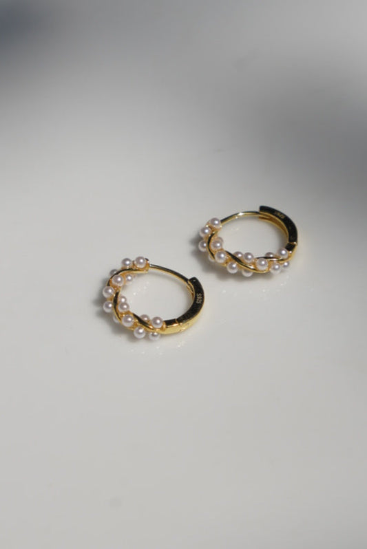 Gold hoop earrings on a white surface with a blurred background