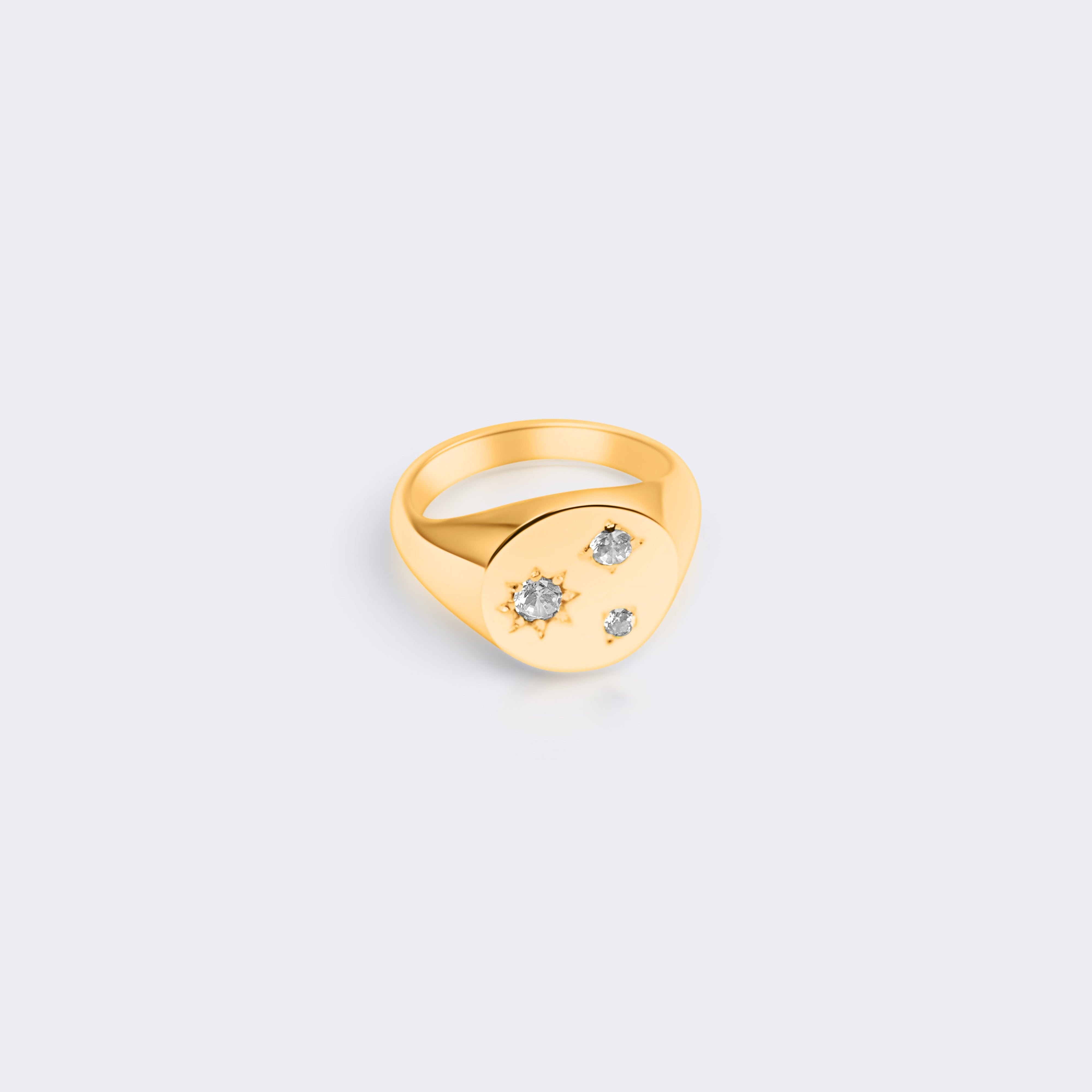 A gold signet ring with a small cluster of clear gemstones on the face