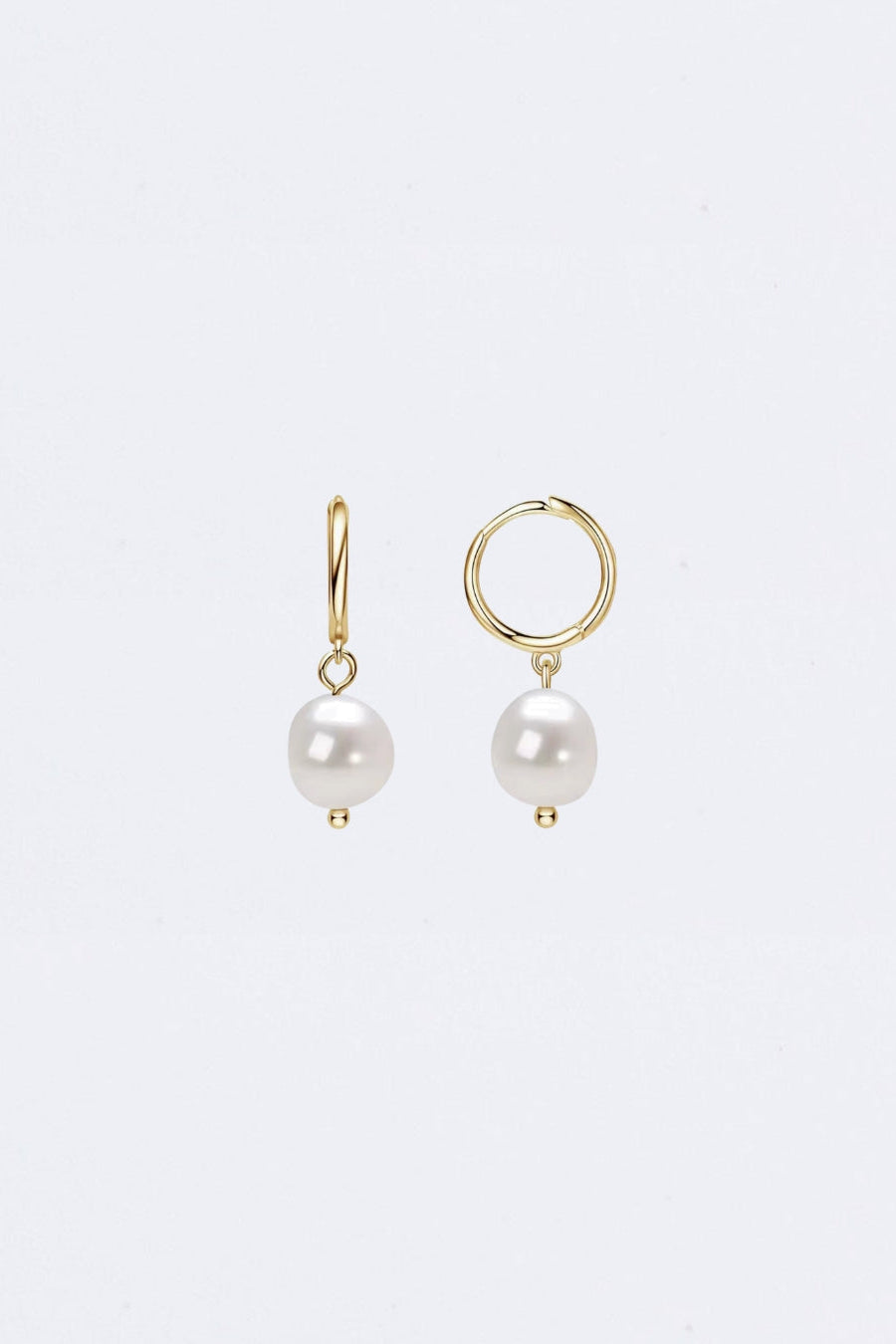 Pair of pearl earrings with gold settings on a light gray background