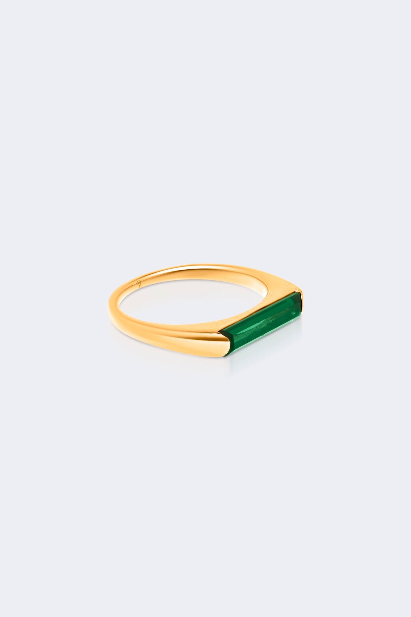 Gold ring with a green gemstone on a light gray background