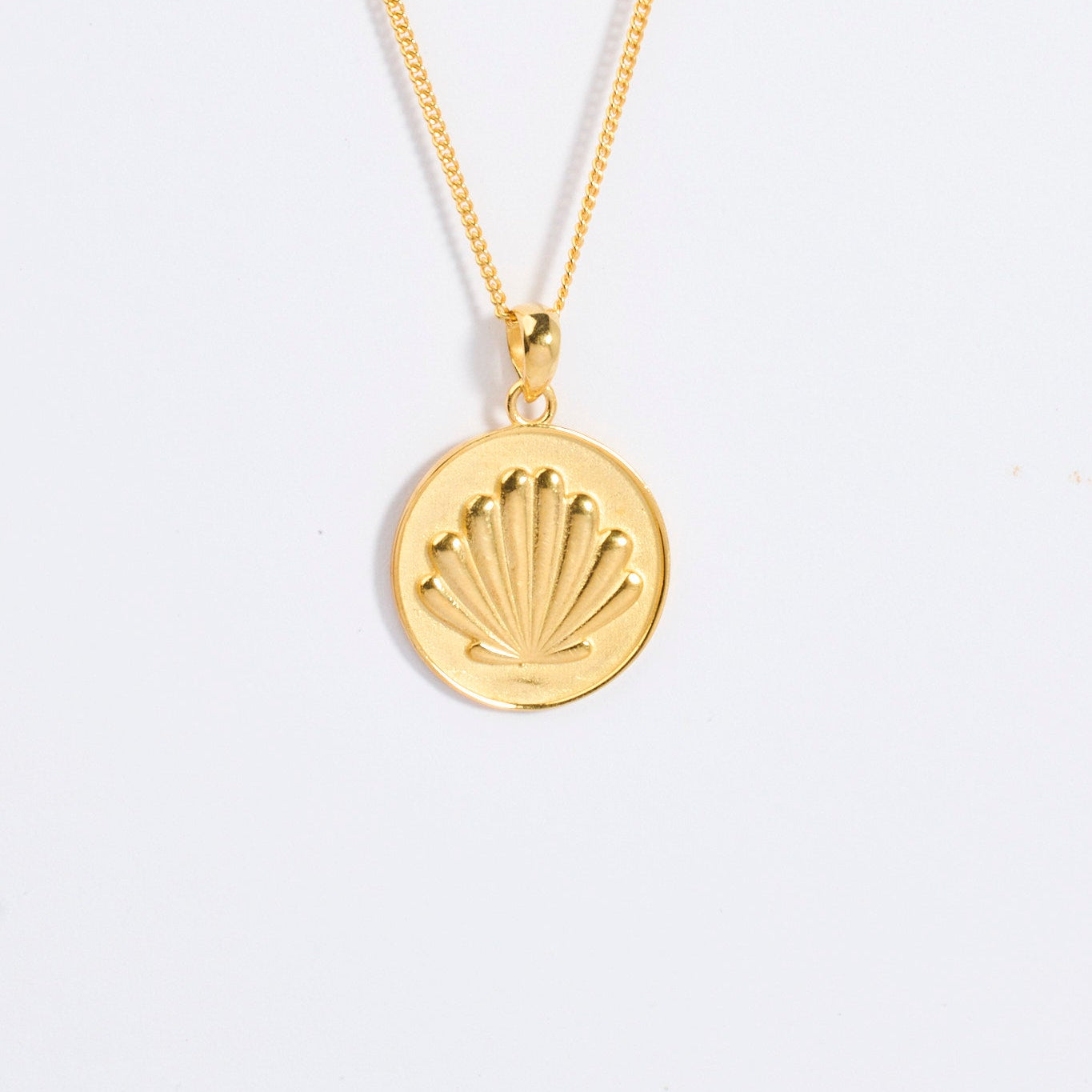 Gold Camino shell necklace with a scallop shell shaped pendant on a light gray background