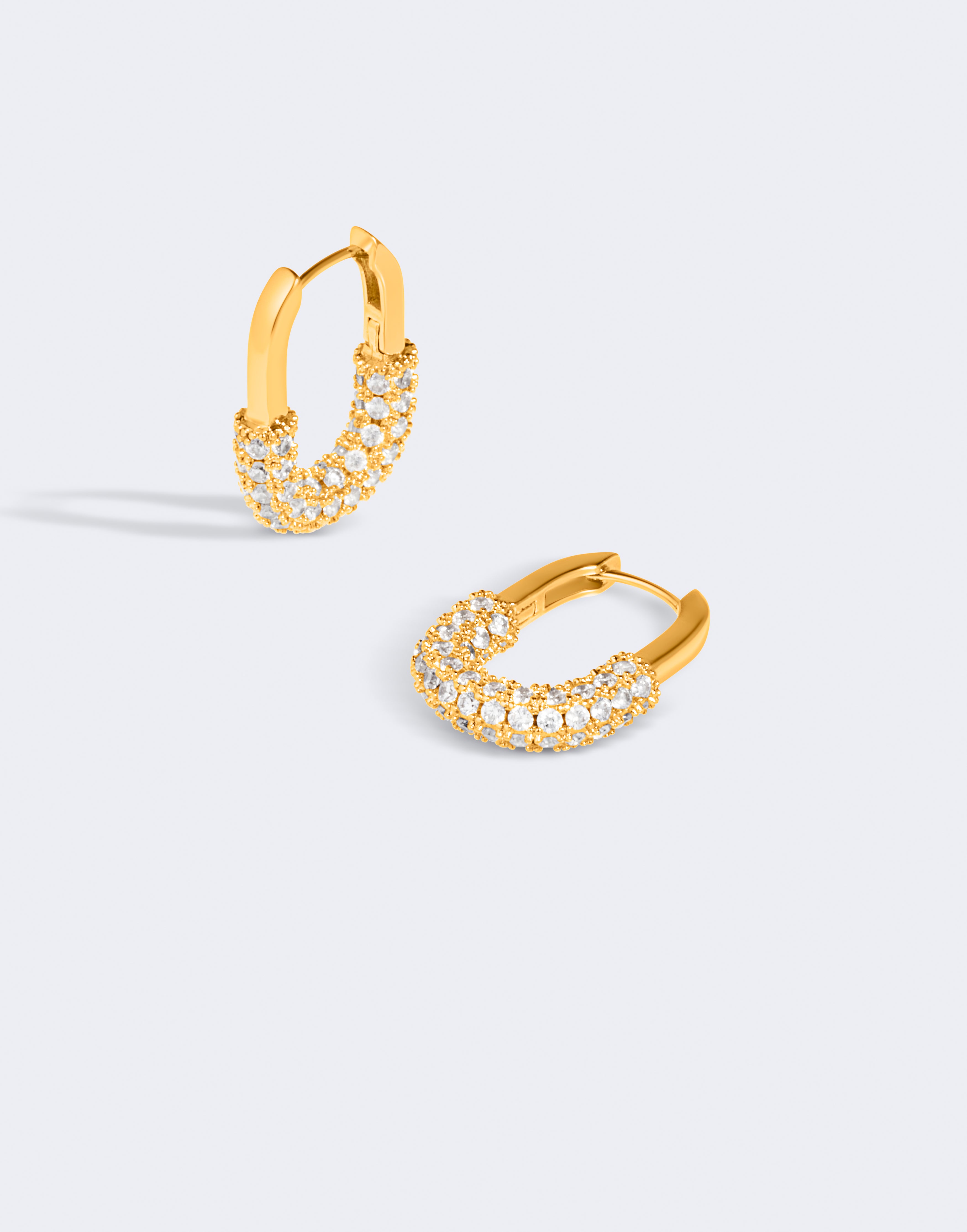 Gold hoop earrings with embedded stones on a light gray background