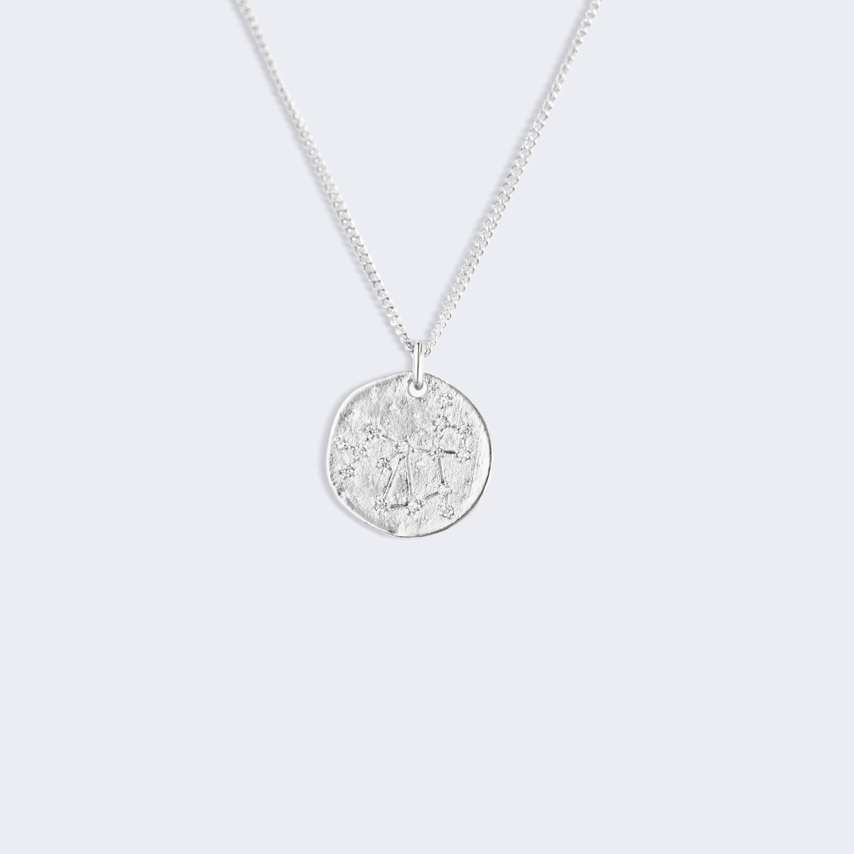 A silver chain necklace with a round, textured coin-style pendant, Sagittarius star constellation zodiac silver 