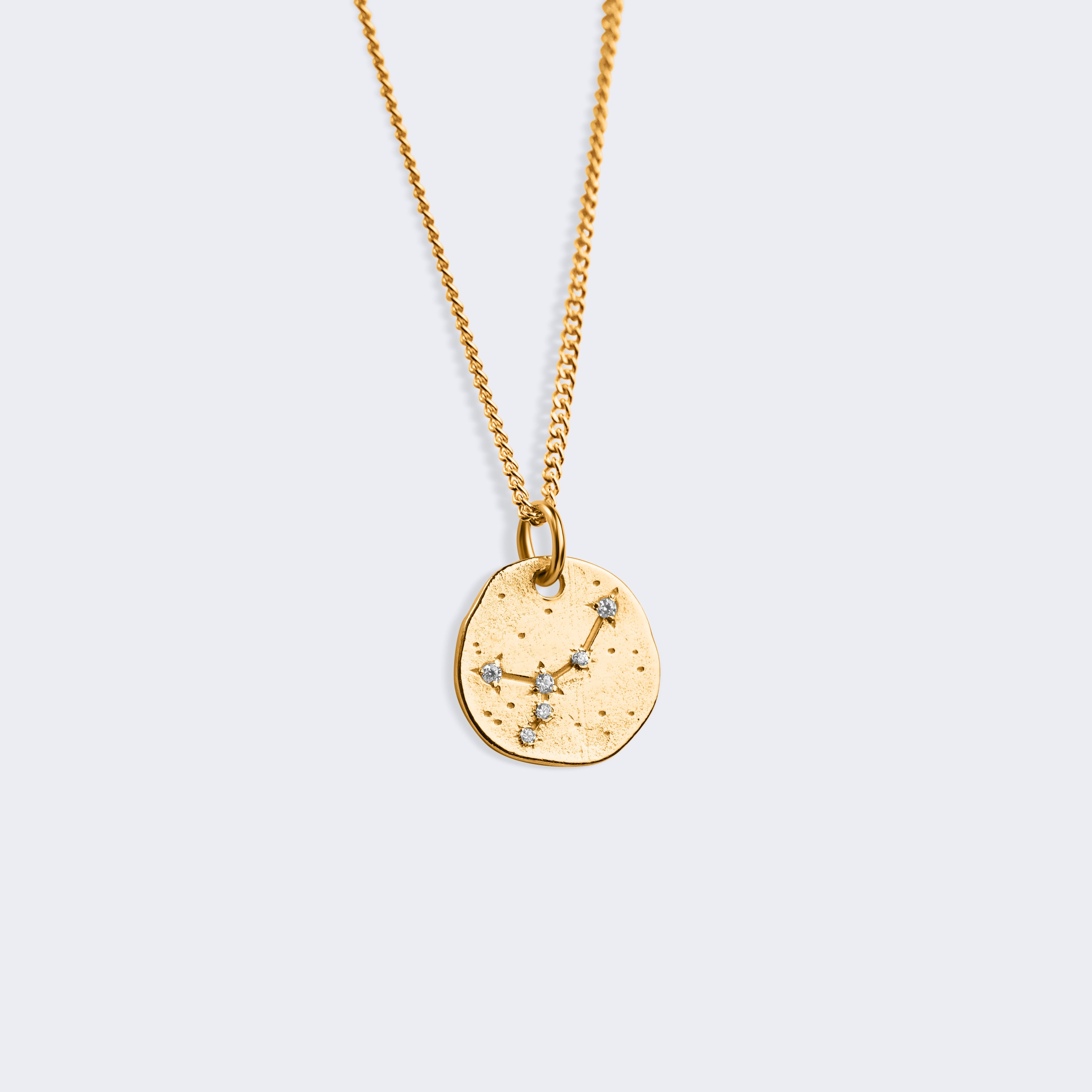 A gold-toned chain necklace with a textured, irregularly shaped circular pendant featuring a cancer star constellation design