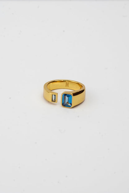Gold ring with a blue gemstone on a white background