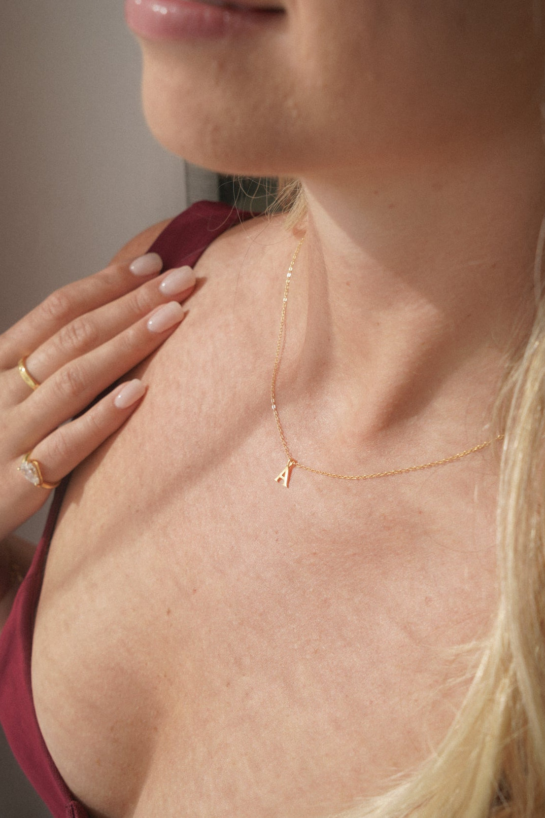 Close-up of a woman wearing a gold necklace with a letter pendant.