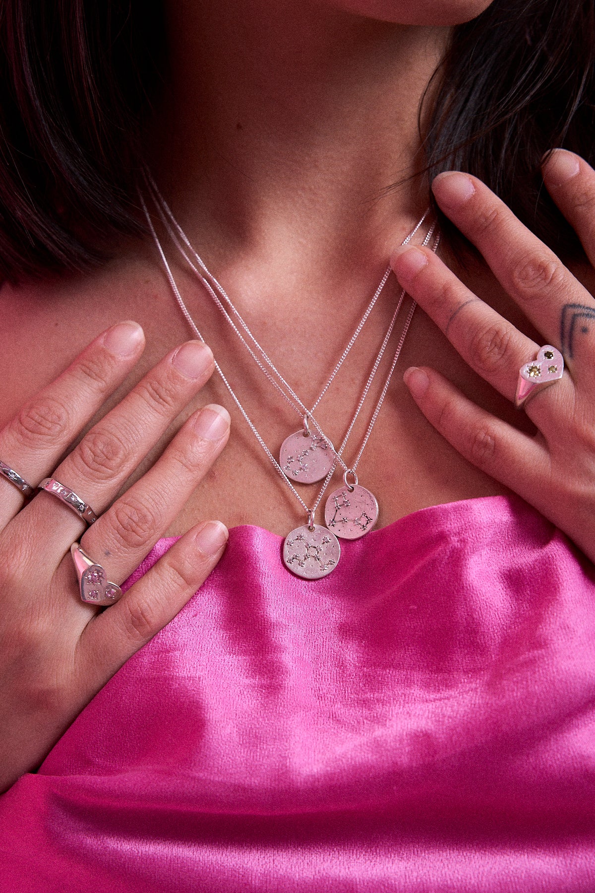 Model wearing layered sterling silver Maraux zodiac constellation necklaces with star signet rings